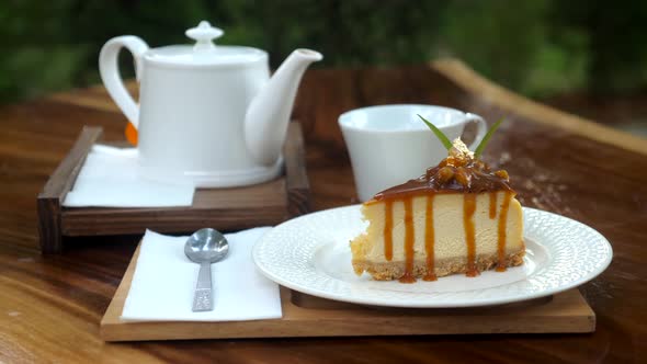 Piece of Delicious Fresh Cake on Wooden Table with White Teapot in Outdoor Cafe alt