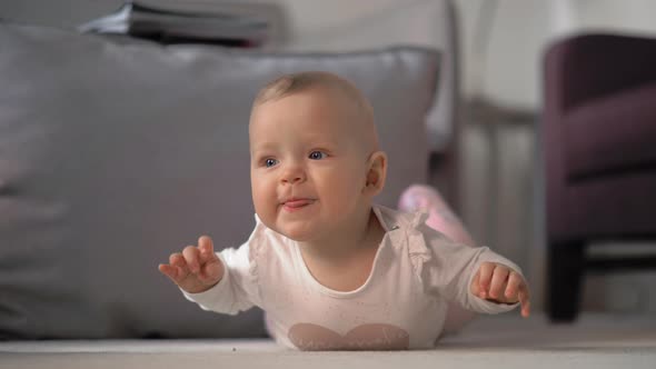 Baby girl on her tummy playing on the floor alt
