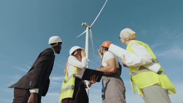Multiracial Coworkers Having Meeting on Farm with Windmills alt