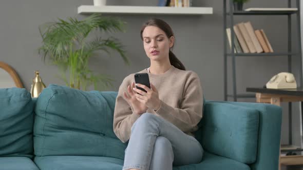 Woman Using Smartphone on Sofa alt