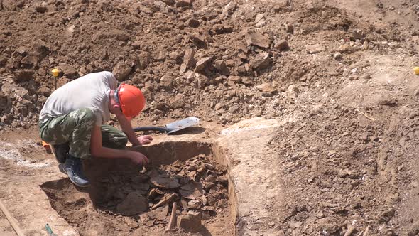 Young Archeologist Works on an Archaeological Site at Morning Sun Rays at Summer Heat alt