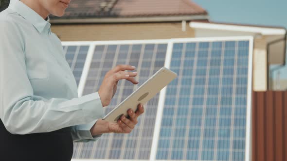Woman with Tablet Standing Before Solar Panels alt