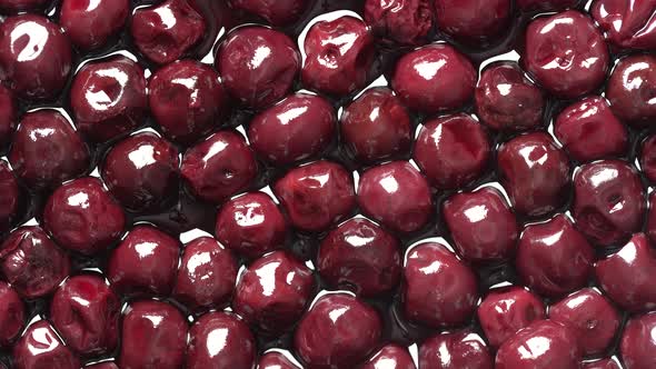 Cherries in alcohol in their own juice in a plate, close up, top view, rotates