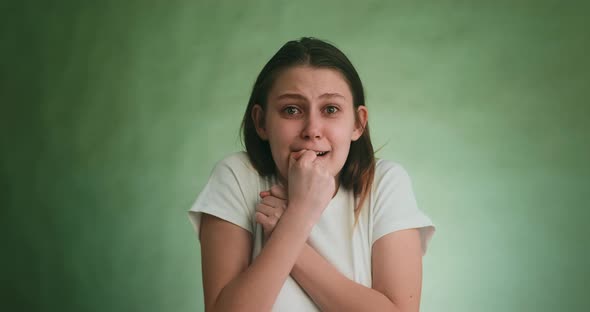 Blonde Lady Holds Fists Near Face Crying with Fear on Green alt