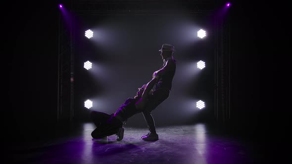Group of Male Gymnasts Perform Acrobatic Stunts on Balancing. Silhouettes of Two Men on a Black alt