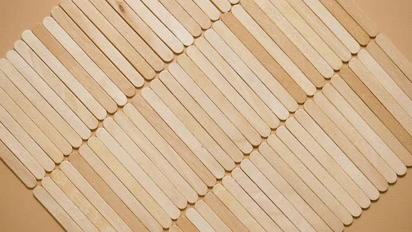 Wooden Popsicle Sticks Placed in a Rows on Top of a Beige Background