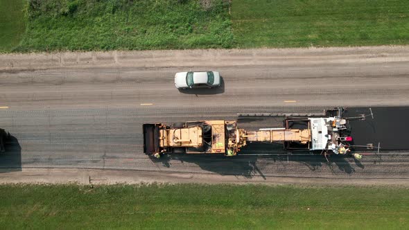 Birds eye view of asphalt paver laying blacktop and dump truck backing ...