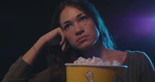 Disappointed woman watching a boring movie at the cinema