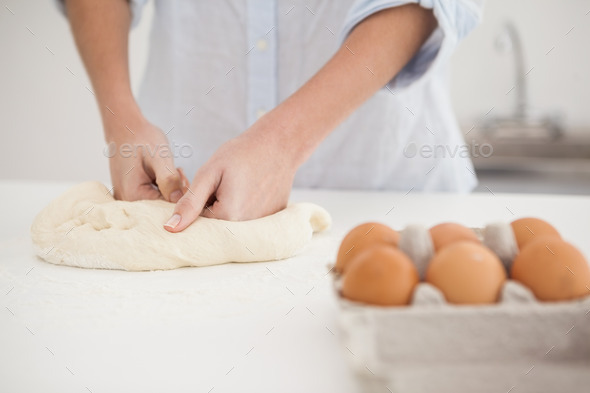 Woman kneading dough on counter at home in the kitchen