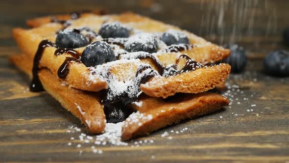 Sprinkle Powdered Sugar Over Belgian Waffle with Chocolate and Blueberries