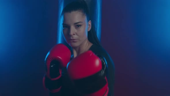 Beautiful  athletic woman boxer in boxing gloves calls her opponent to battle and smiles ironically alt