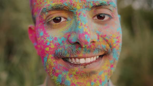 Closeup Slow Motion Portrait of Handsome Arab Guy with Painted Face Standing Outdoors at Holi alt