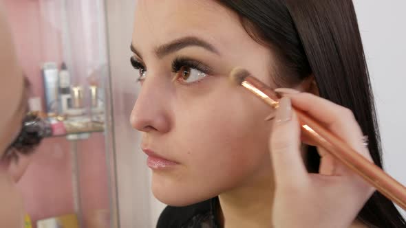 A Professional Makeup Artist Applies Grey Eyeshadow with a Special Brush in a Makeup Studio alt