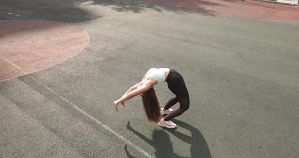 Athletic Woman Is Doing Yoga Wheel Pose Practicing on Stadium and Standing Up.