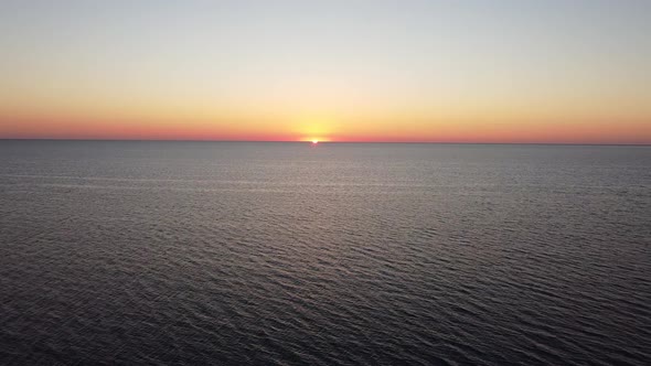 Bird's Eye View of the Calm Water Surface of the Sea During the Orange Evening Sunset on the Horizon