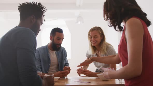 Two couples having fun while playing cards at a table alt