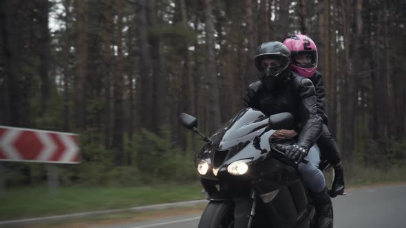 Couple of Motorbikers Passing Camera and Leaving. Young Confident Man and Woman in Helmets Riding on alt