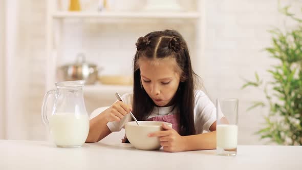 Cute Little Girl Eating Breakfast: Cereal with the Milk.