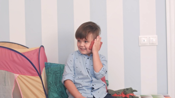 Smiling Little Boy Talking on Mobile Phone in His Room