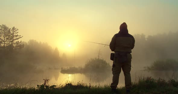 Unrecognizable Man Fishing in Lake at Dawn