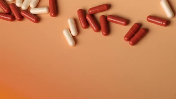 Red and white pills falling on table with tablets pharmaceutical industry alt