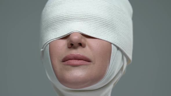 Woman Covered in Elastic Bandage Showing Silence Sign, Illegal Plastic Surgery