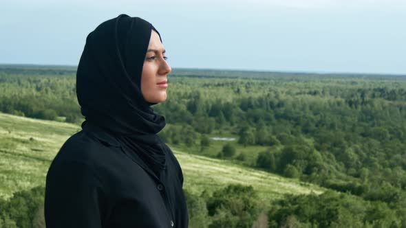Pleasant Muslim Woman Breathing Freedom Inspiration on Top of Mountain Over Green Grass Forest alt