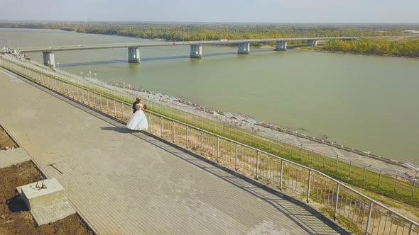 Just Married Couple on Hilly Embankment Near River Aerial alt
