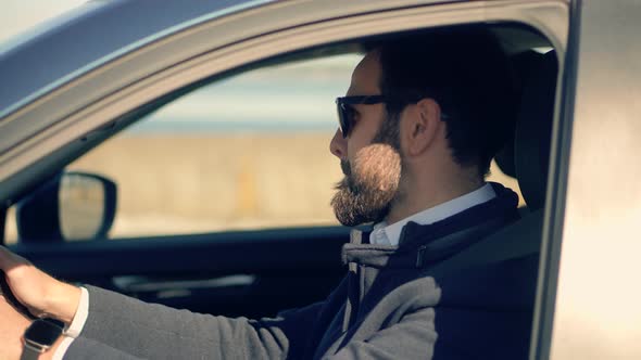 Male Driver Turning Steering Wheel In Car. Man Driving Auto And Using Controls In Car. alt