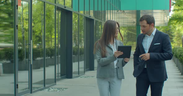Business People Going To Work with Digital Tablet on Street. Man and Woman Walking Near Office in
