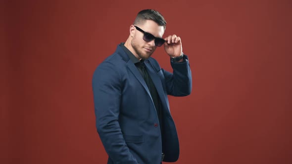 Portrait of handsome businessman. Stylish man taking off black glasses on the studio background. alt