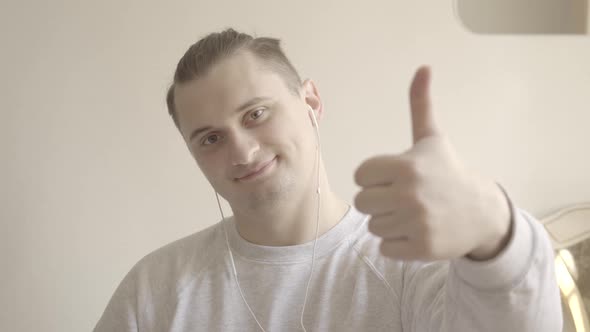 Close-up of Cheerful Young Man Showing Thumb Up at Camera. Portrait of Smiling Young Caucasian Guy alt