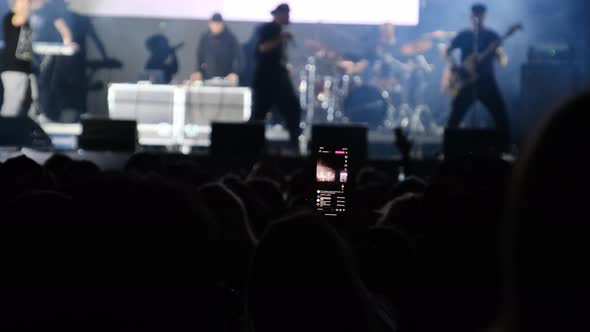 People at the Rock Concert Broadcast Live on Social Networks Using a Smartphone alt