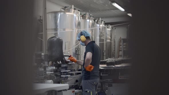 Male Worker In Mask Operating Beer Production Equipment During Working Process  Medium alt