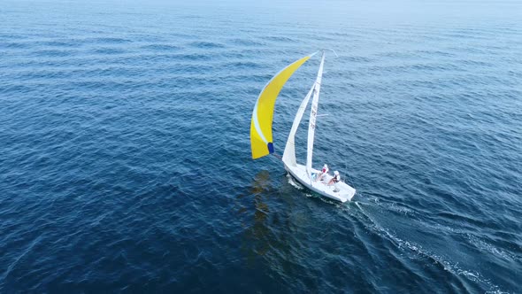 Sea regatta. A beautiful white yacht with a yellow sail sails in the blue sea alt