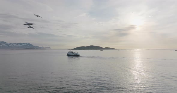 Ferry cruising on fjord at sunset, scenic calm arctic ocean; aerial alt