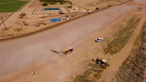 Drone shot of building a dirt wall or border for a rock quarry, spraying rocks on the side of the hi alt