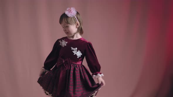 Cute Little Girl in an Old Burgundy Dress is Spinning in the Dance and Rejoicing