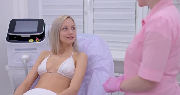 Young Beautiful Woman Is Pleased with the Cosmetic Procedure, Thanks the Beautician. Beautician alt