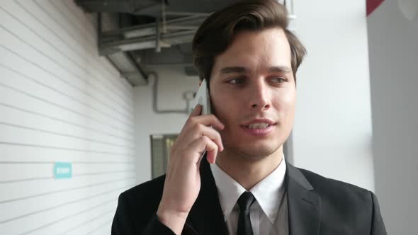 Businessman Walking and Talking on Phone in Office, Close Up alt