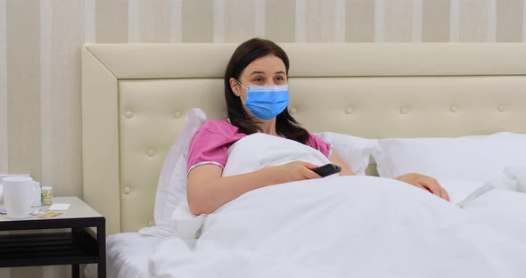 Woman with Medical Mask Suffering from Covid 19 Watching TV at Home