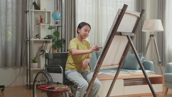 Girl In Wheelchair Holding Paintbrush Mixed Color And Thinking Before Painting On The Canvas alt