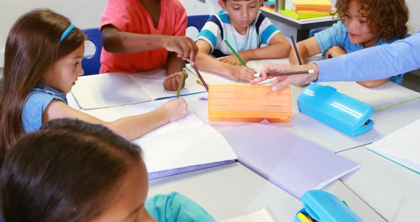 Teacher helping kids with their homework in classroom alt