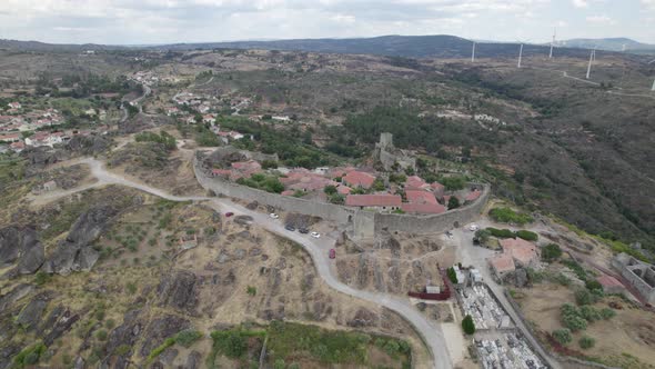 Aerial descending wide panoramic view of Sortelha village and wind turbines for eolic energy