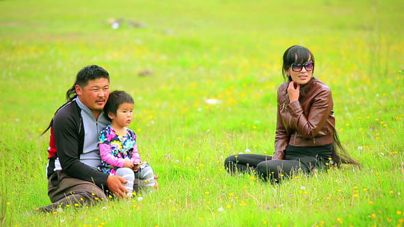 Mongolian Family Sitting On Grass