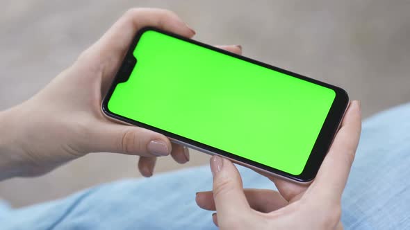 Closeup of Hands Using Smartphone with Blank Green Screen Horizontally alt