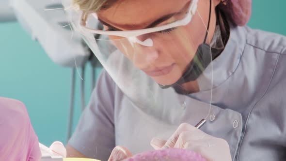 Professional Female Dentist with Assistant Perform an Operation in Dental Clinic