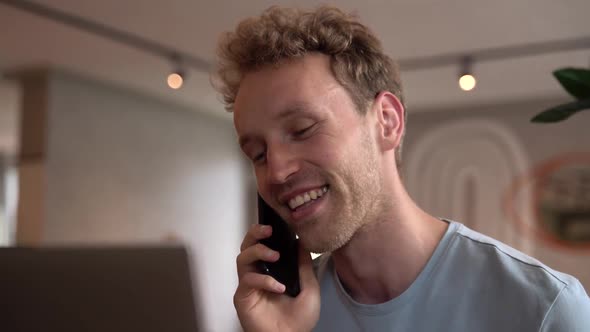 Smiling, positive guy talking on the phone indoors alt