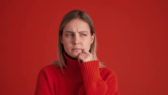 Displeased woman wearing red sweater showing silence gesture at the camera alt