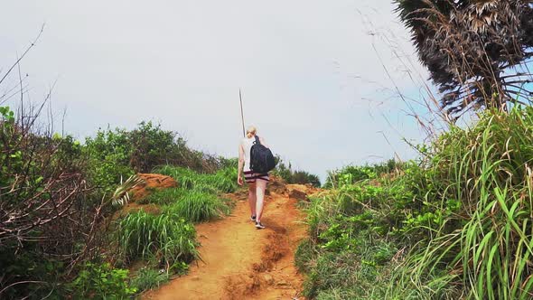 travel on a tropical island, a girl climbs uphill to see the seascape alt